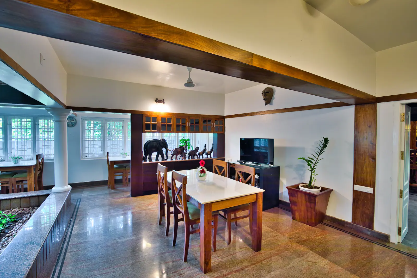 Dining hall with wooden tables beside an indoor courtyard garden at an Ayurveda retreat in Kerala