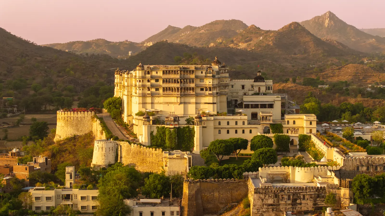 Restored hilltop fort palace above its gardens at sunset in the Aravalli hills near Udaipur