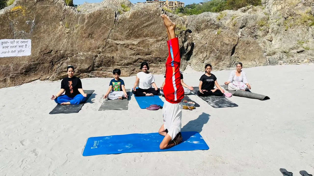 Small group stretching with yoga straps overhead in an indoor yoga hall in Rishikesh