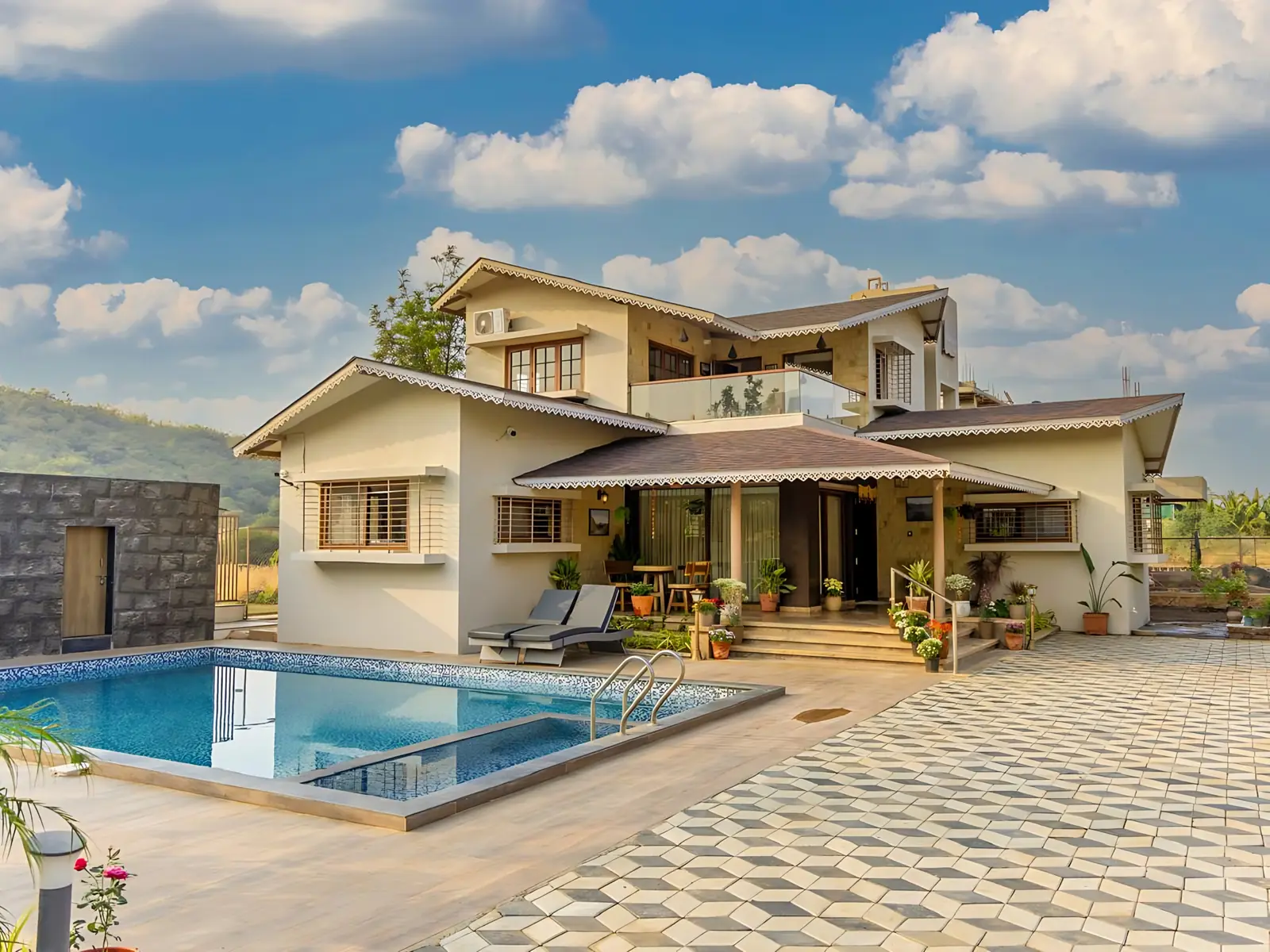 Aerial view of white cottages with red roofs and a pool among palms at an Ayurveda resort in Abu Road
