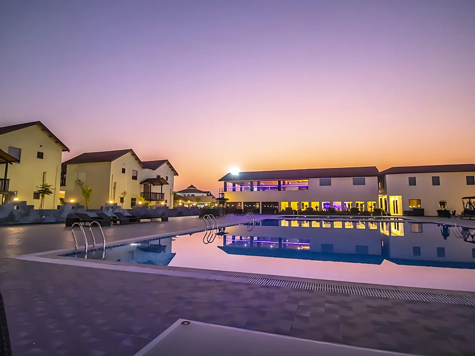 Swimming pool and cottages at sunset at a wellness retreat near Mount Abu in Rajasthan