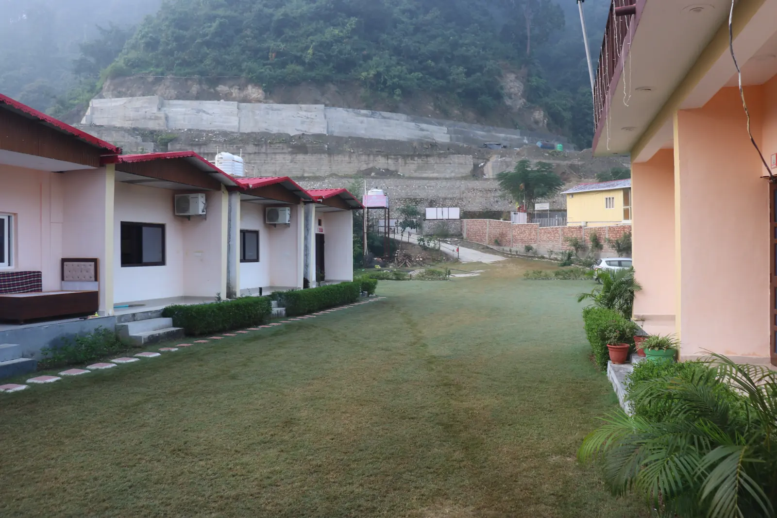 Students seated in a circle on a lawn outside cottages during a course in Rishikesh