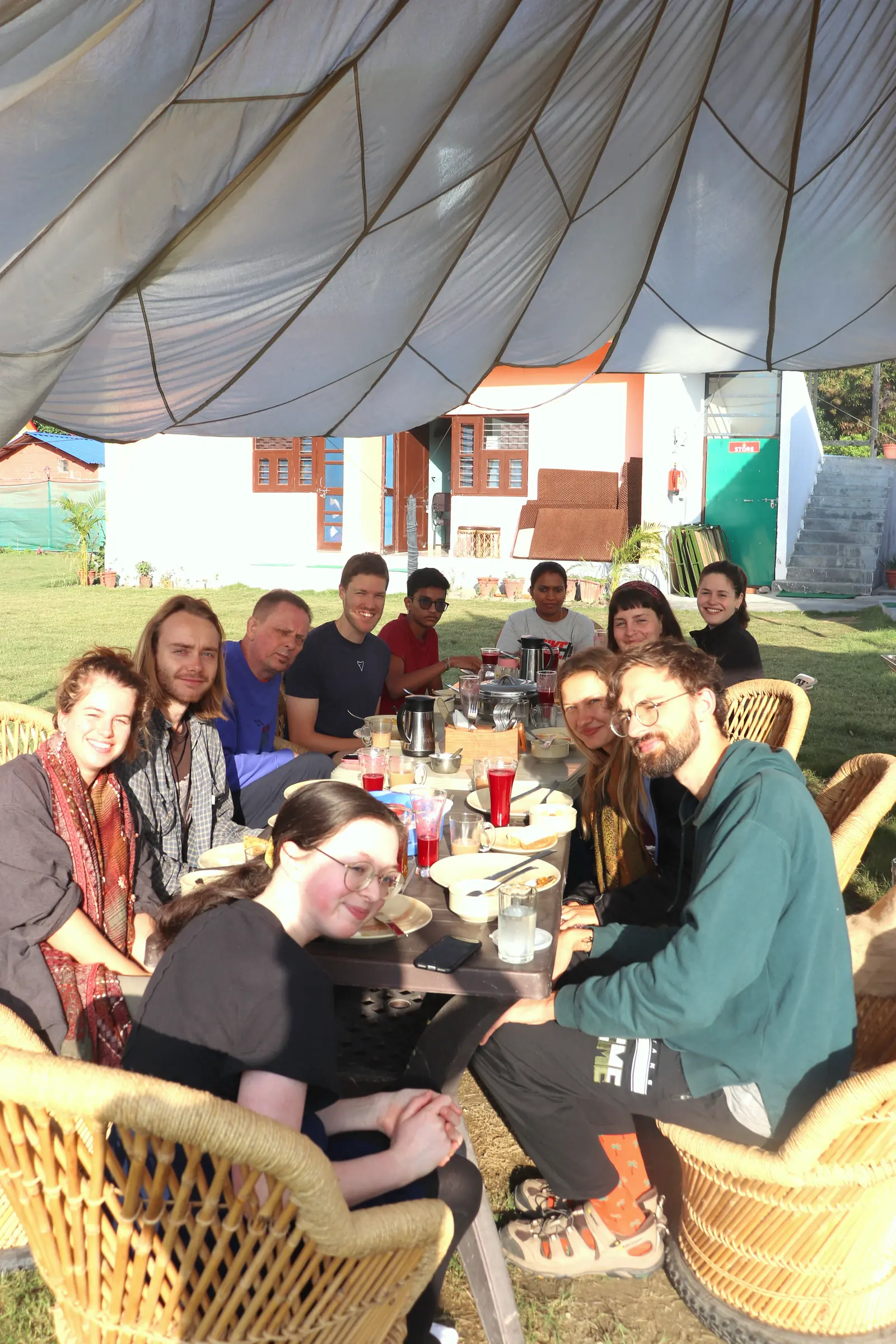 Students seated in a circle on a lawn outside cottages during a course in Rishikesh