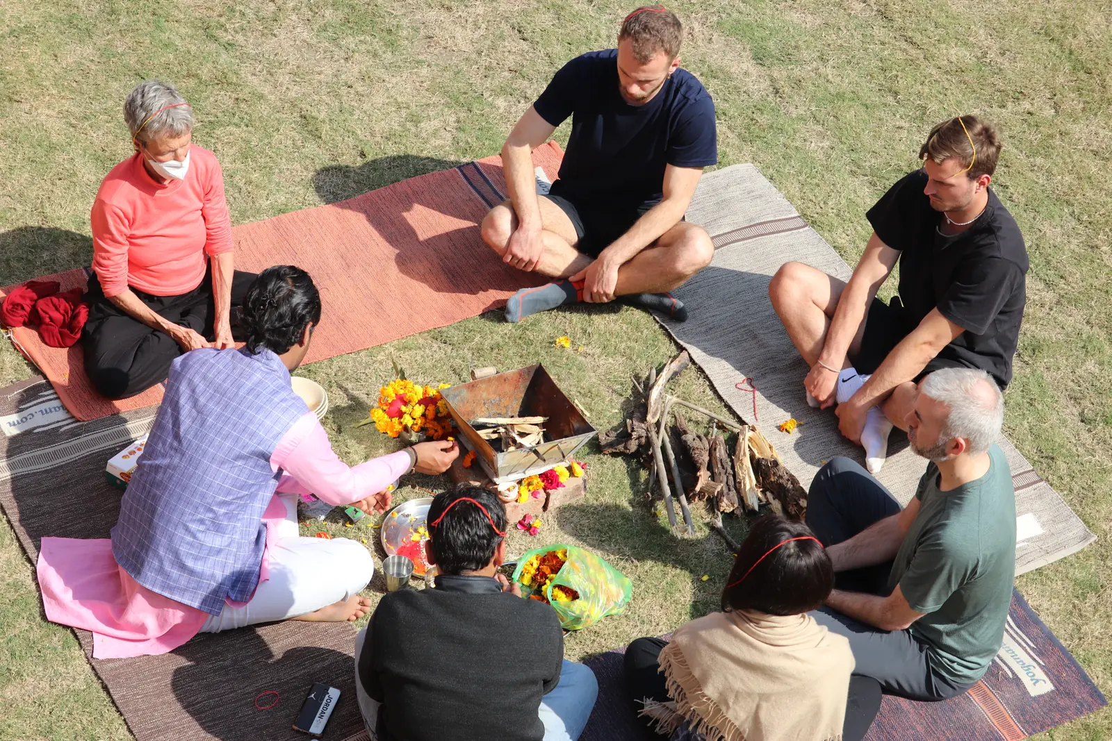 Students seated in a circle on a lawn outside cottages during a course in Rishikesh