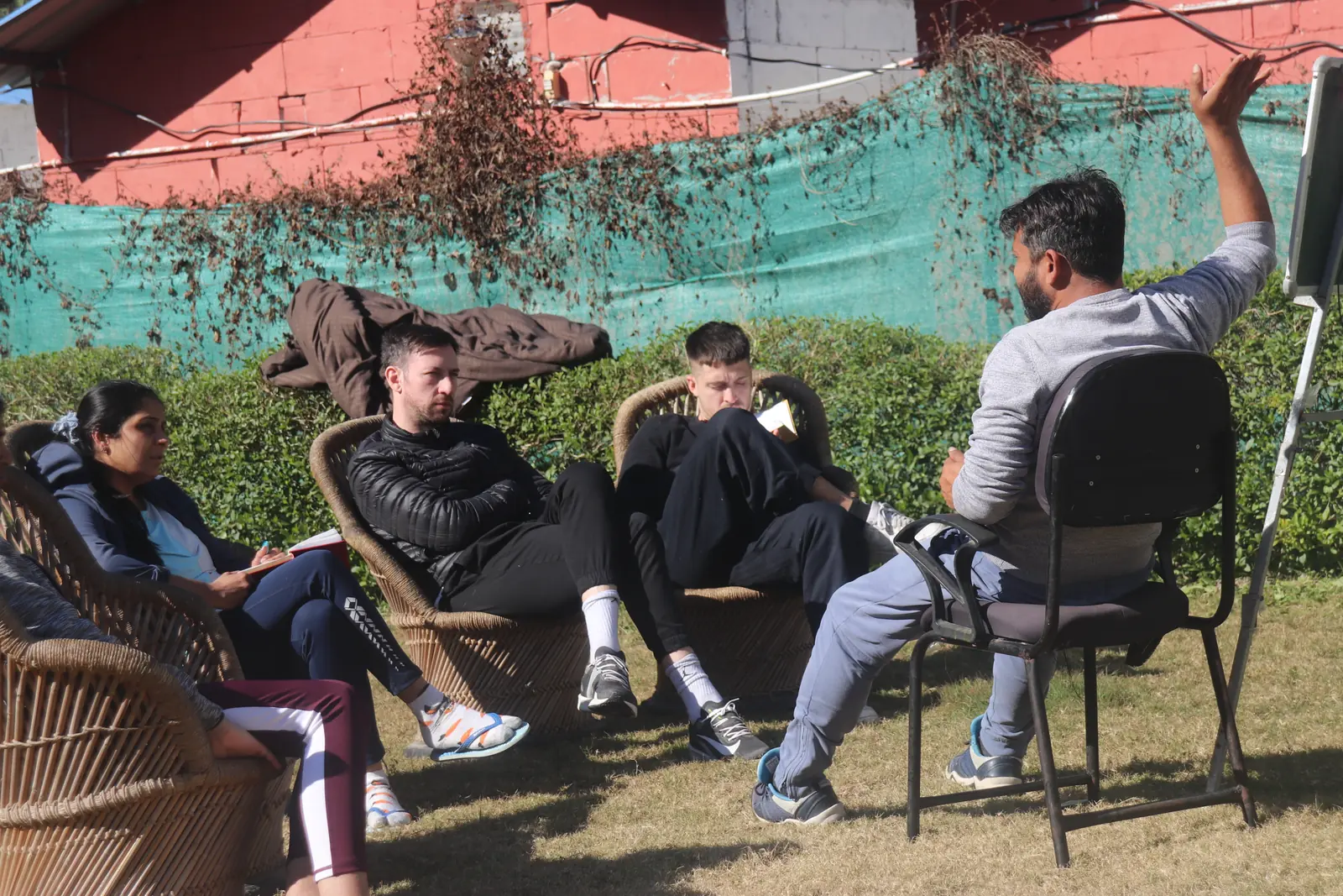 Students seated in a circle on a lawn outside cottages during a course in Rishikesh